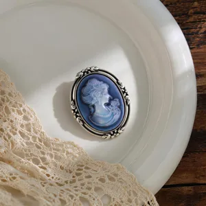 Close-up of vintage blue cameo brooch with silver ornate frame on white plate with lace