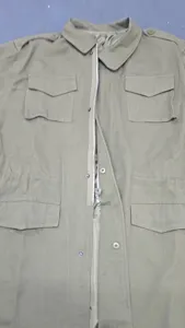 Detailed view of the functional pockets and front zipper on olive green military style jacket
