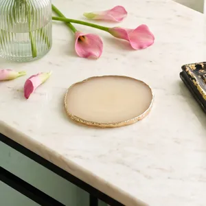 Detailed view of cream resin agate nail palette with golden trim on marble top