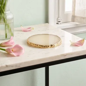 Close-up of elegant gold-edged white resin agate nail palette on a luxury marble surface.