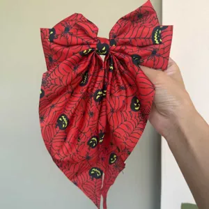 Detailansicht einer großen Halloween-Haarschleife mit roten Spinnennetz-Kürbis-Prints.