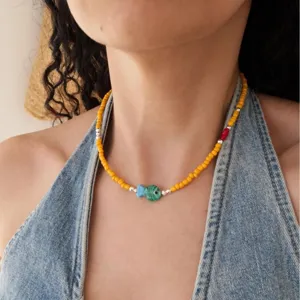 Vue détaillée d'un collier de perles jaunes avec un pendentif poisson en verre vert