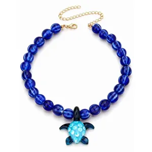 Collier de perles de verre bleu vif avec un pendentif tortue de mer et une chaîne dorée.