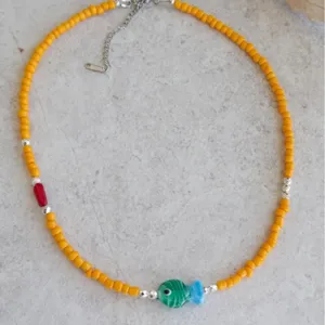 Vue détaillée d'un collier de perles orange fait main avec un pendentif en poisson de verre