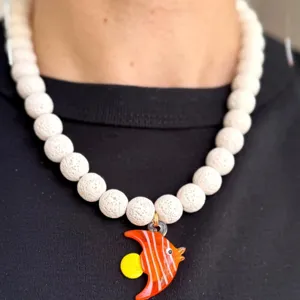 Vue détaillée du collier en perles de lave blanche avec un pendentif poisson en verre orange