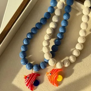 Gros plan d'un collier de perles fait main avec des pendentifs poissons en verre