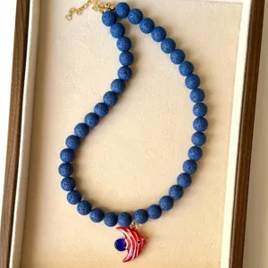 Détail du collier en perles de pierre de lave bleue avec pendentif poisson en verre