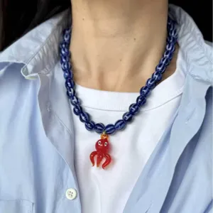 Gros plan d'un collier en perles bleues avec pendentif poulpe en verre rouge