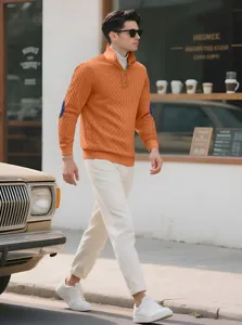 Men's orange jacquard knit quarter-zip sweater styled with white pants on city street.