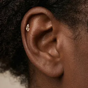 Close-up of a butterfly shaped gold cartilage piercing stud with sparkling crystals