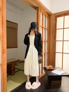 Model wearing cozy white cross-strap fuzzy slippers in a minimalist indoor setting