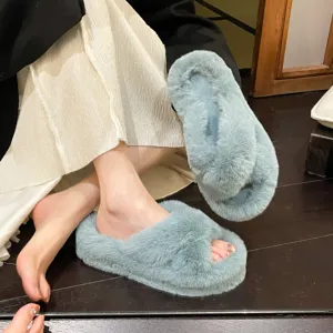 Close-up of light blue plush faux fur slippers with elegant platform cross-strap design.