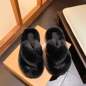 Close-up detail of black cross-strap fluffy slippers placed on a cardboard box background
