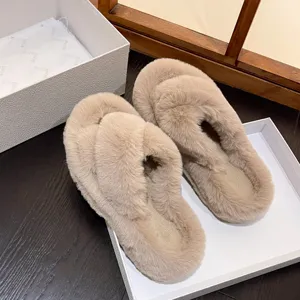 Detailed view of plush beige cross-strap slippers placed on a dark wooden surface.