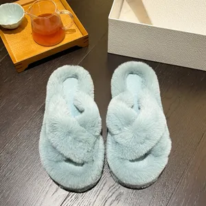 Close-up of soft light blue faux fur cross-strap slippers on wooden floor