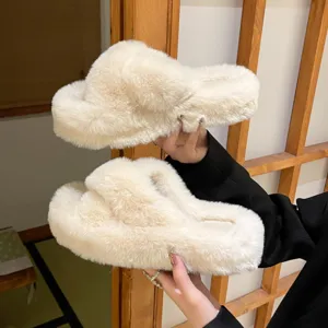 Close-up detail of cream white furry criss-cross slippers with thick soles held by hand