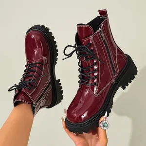 Gros plan de bottines à plateforme en cuir verni bordeaux avec surpiqûres blanches.
