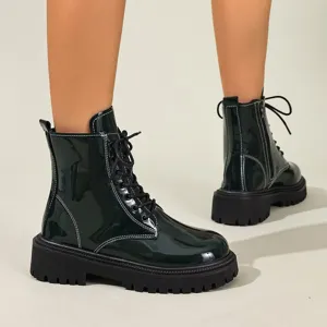 Détail de bottines Martin en cuir verni vert foncé avec semelles épaisses et coutures blanches.
