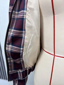 Detailansicht einer burgunderroten Karojacke mit glattem cremefarbenem Satinfutter