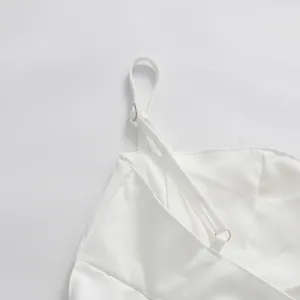 Close-up detail of white satin dress strap and adjustable silver metal ring buckle