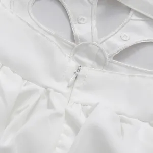 Close-up view of white dress with hollow-out embroidery and invisible zipper detail.