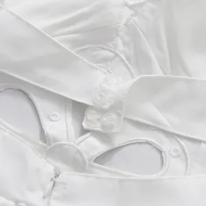 Macro detail of white hollow-out embroidery and snap buttons on the back of the dress