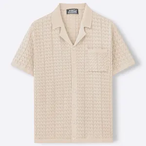 Close-up view of men's beige jacquard knit button-up shirt with a Cuban collar and pocket.