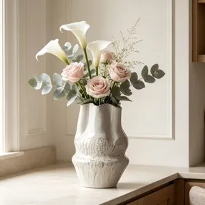Dettaglio di un vaso in ceramica bianca testurizzata Wabi-sabi con fiori in un interno