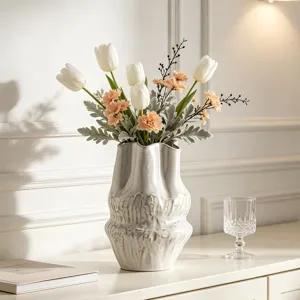 Dettaglio di un vaso in ceramica bianco sporco con trama ondulata in un ambiente moderno.