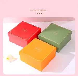 Close-up of square gift boxes in vibrant red, green, and orange with gold accents and patterns.