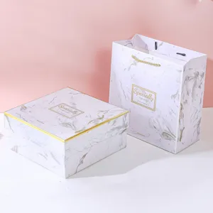 Detail view of a white marble pattern gift box and matching paper bag with gold text
