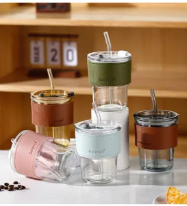 Glass tumblers with colorful leather sleeves and glass straws shown in a lifestyle set.
