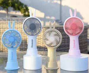 Four colorful portable mini fans with rabbit ears standing on a table outdoors.