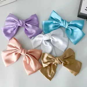 Detalle que muestra cinco pinzas para el cabello con lazo de satén en varios colores.