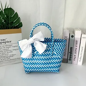 Detalle de un bolso tejido a mano en azul y blanco que incluye un elegante lazo blanco grande.