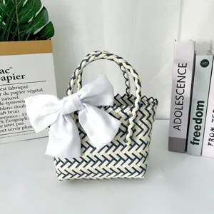 Vista detallada del bolso de regalo tejido a mano con un gran lazo decorativo blanco