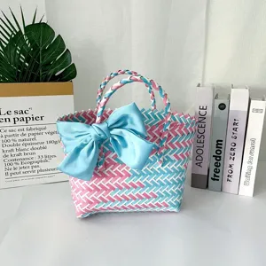 Detalle de bolso tejido a mano de colores con un gran lazo decorativo de satén azul claro.