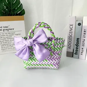 Bolso tejido colorido hecho a mano con un gran lazo de satén morado en decoración lifestyle.