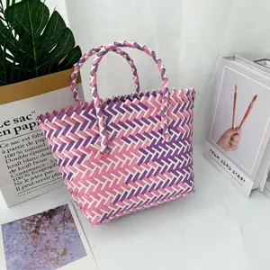 Vista detallada del bolso tejido a mano con intrincados patrones en rosa y púrpura.