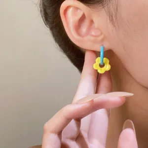 Nahaufnahme eines süßen gelben Blumen-Ohrrings mit mattem Finish, getragen von Model