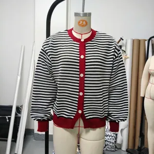 Detailed view of black and white striped knit cardigan with red ribbed trim on a mannequin display.