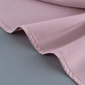 Gros plan sur la texture du tissu rose et la couture fine de l'ourlet d'un costume.