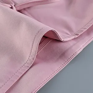 Détail d'un haut chinois en satin rose avec bouton nœud traditionnel et coutures fines.
