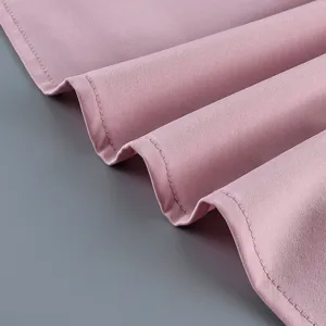 Makro-Detail eines zartrosa Faltenrocksaums mit präzisen Nähten und glatter Stofftextur