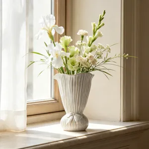 Elegante nordische weiße Keramikvase mit Blumen auf einer sonnigen Fensterbank