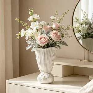 Elegante weiße geriffelte Keramikvase mit Schleifendetail und rosa Rosen auf einem Tisch
