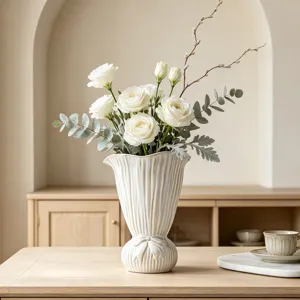Detailansicht einer modernen weißen Keramikvase mit Faltenstruktur und Schleifendetail.