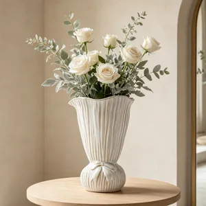 Elegante cremeweiße Keramikvase mit Faltenstruktur und Schleifendetail mit weißen Rosen.