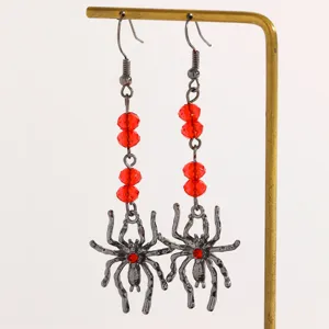 Gothic gunmetal spider dangle earrings with faceted red beads on a display stand