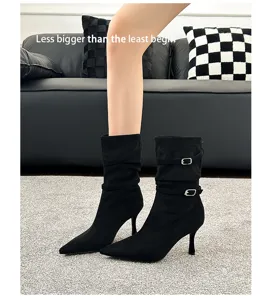 Close-up of black pointed-toe stiletto ankle boots with buckle and pleated details